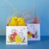 Petits paniers de Pâques en papier décorés de poussins et de fleurs présentés avec des mini-poussins en chenille jaune.